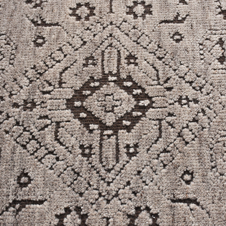 Inkwell hand-knotted ivory wool rug with a faded black tribal medallion, in a living room