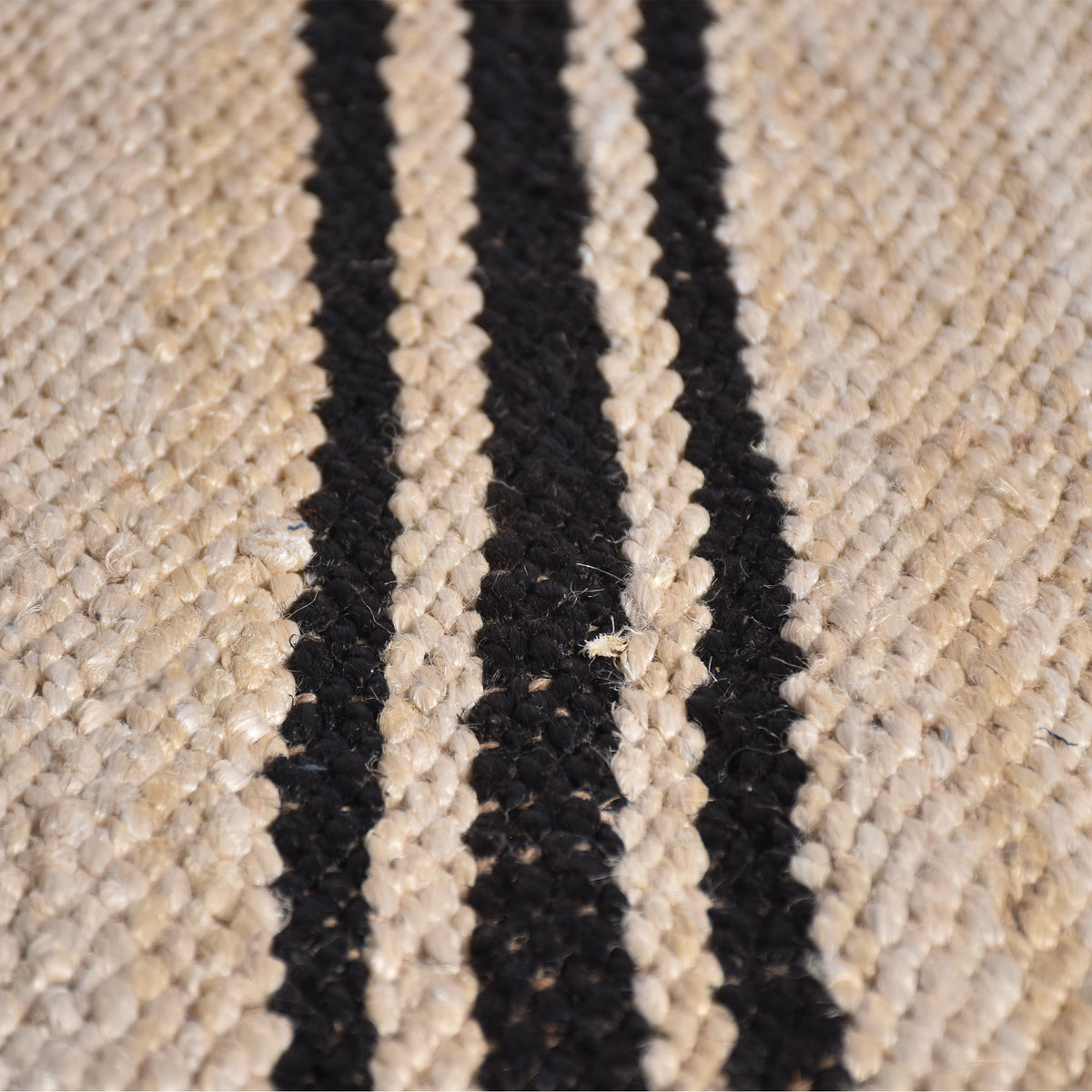 Khaat handwoven natural jute rug with black stripes, in a living room
