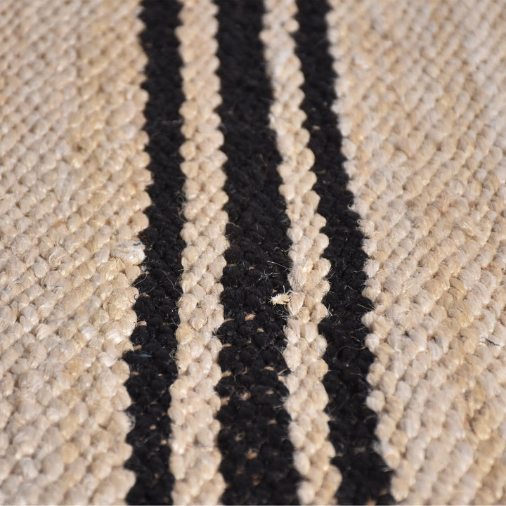 Khaat handwoven natural jute rug with black stripes, in a living room
