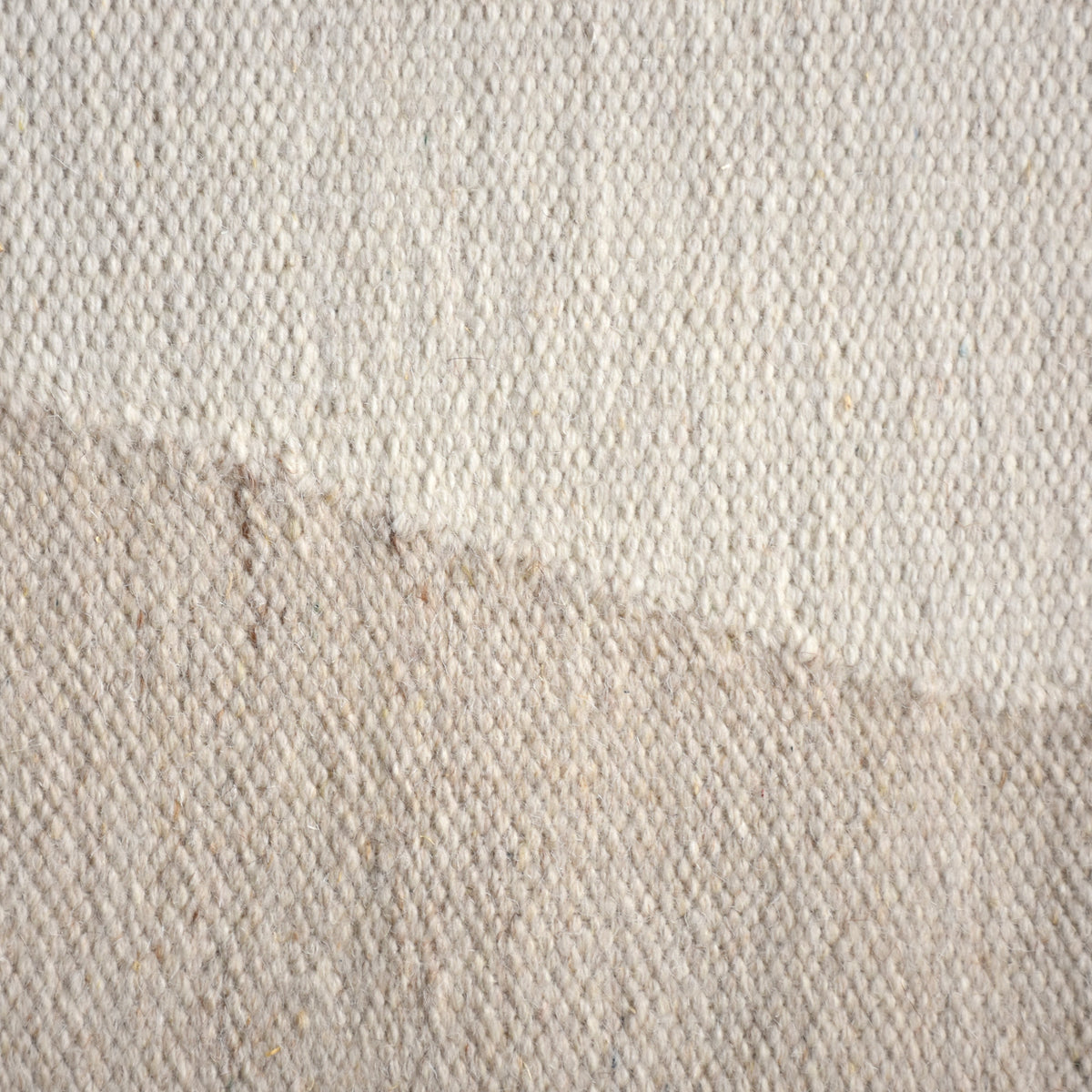 Kamaan handwoven wool flatweave rug with overlapping ivory and beige arcs, in a living room