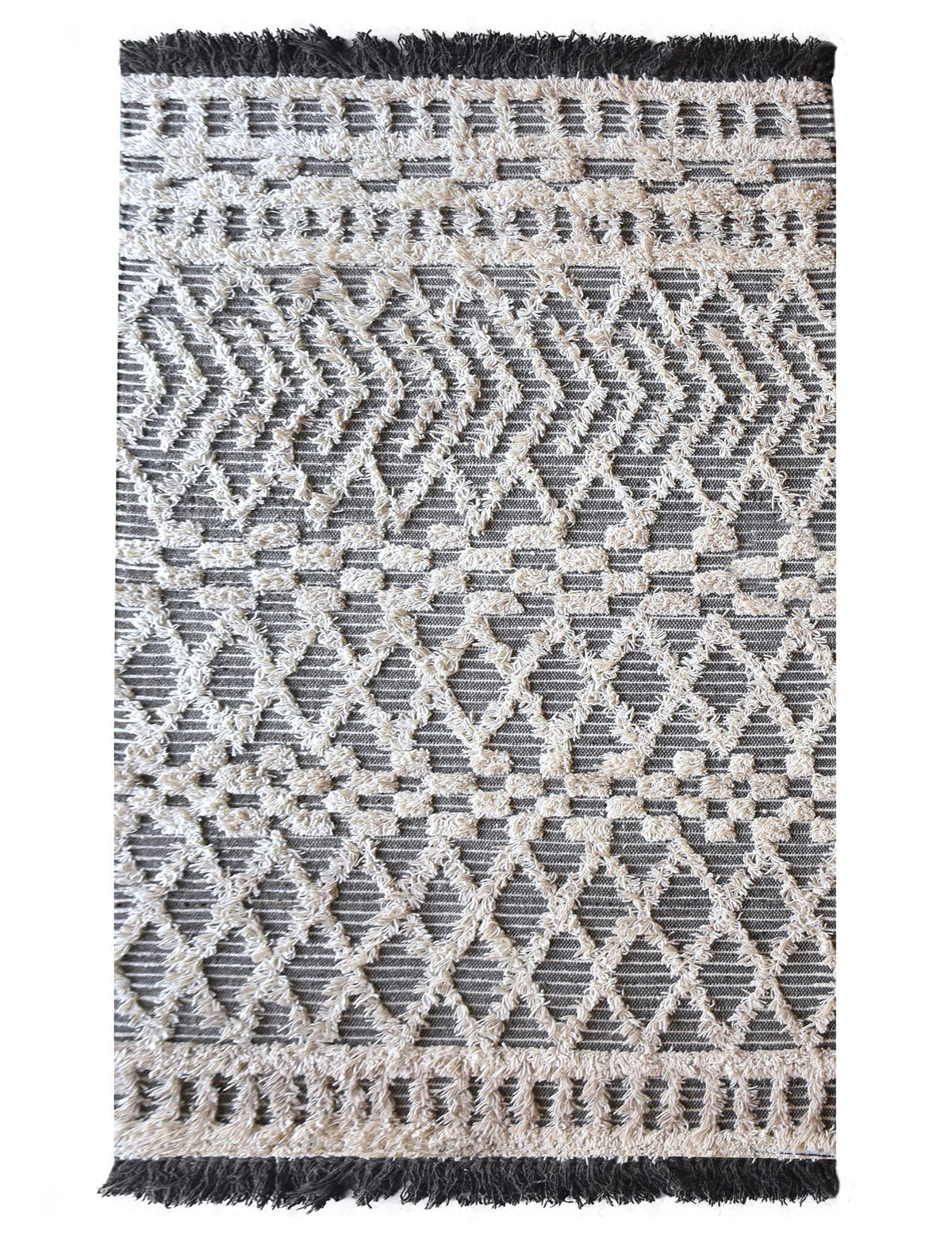 Tassel tufted wool rug with charcoal and ivory chevrons and shaggy bands, in a bedroom
