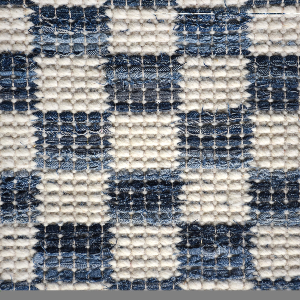 Taash handwoven denim and cotton rug with a navy and ivory checkerboard, in a living room