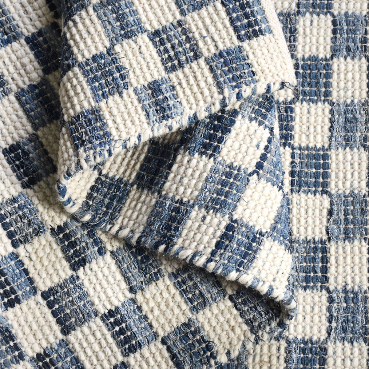 Taash handwoven denim and cotton rug with a navy and ivory checkerboard, in a living room