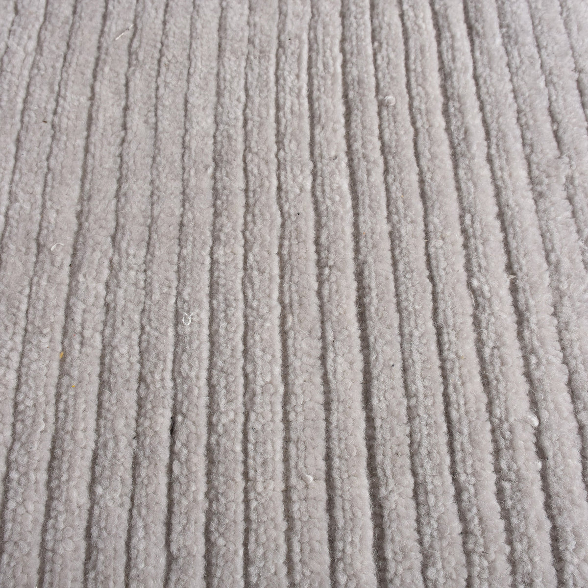 Megh handwoven NZ wool rug in light grey with wide ribbed vertical bands, in a living room