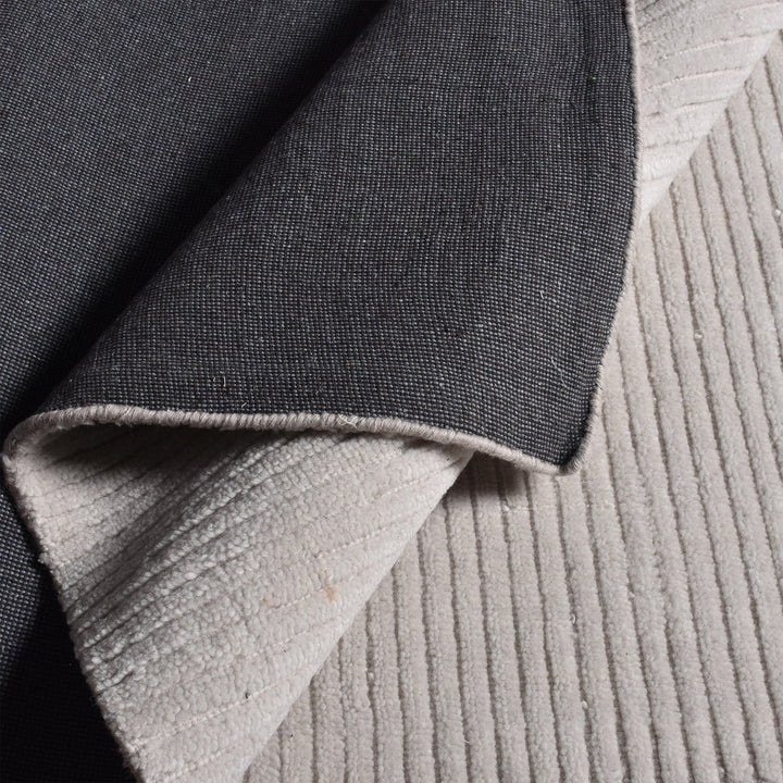 Megh handwoven NZ wool rug in light grey with wide ribbed vertical bands, in a living room